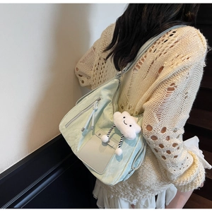 Detail of light green tote bag with texture, side pocket and cute cloud charm accessory