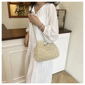 Detail of beige woven straw handbag with a gold metal chain strap on white lace dress