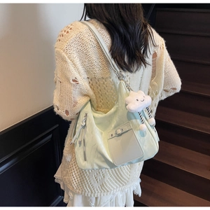 Detail of mint green commuter bag with glossy texture and cloud pendant accessory