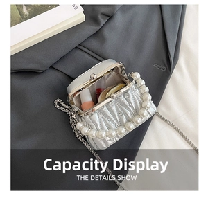 Detail view of silver pleated clutch showing pearl handle and interior storage capacity