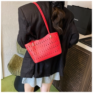 Detalle del bolso tote de cuero rojo calado con motivos cortados con láser y herrajes plateados