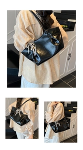 Détail du sac cabas noir brillant avec nœud en dentelle blanche et pendentif perle