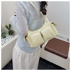 Detail of cream yellow PU leather shoulder bag featuring multi-pocket utility design