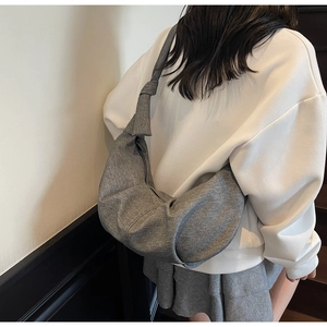 Close-up of grey knit crescent bag with stylish knot strap and zipper detail