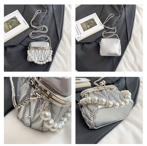 Macro detail of silver pleated mini bag with pearl handle and rhinestone metal clasp