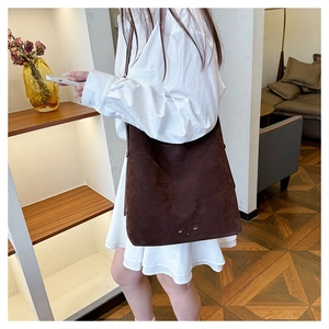 Detail of dark brown suede tote bag with golden metal rivets on the bottom