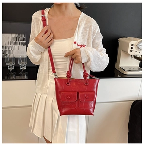Detail of red crocodile texture handbag with knotted handle and decorative front pockets