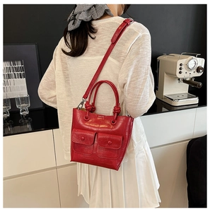 Detail of red crocodile texture handbag with unique double flap pockets and knotted handle