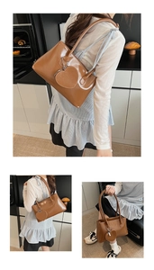 Detail view of brown glossy leather shoulder bag with matching heart-shaped charm accessory
