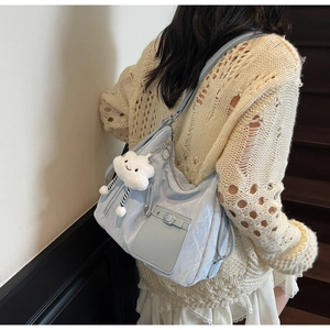 Close-up of light blue shoulder bag featuring textured fabric and a white cloud charm