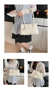 Detail view of cream leather underarm bag with minimalist heart pendant and slim straps