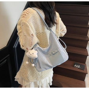 Detail of light blue textured shoulder bag with a fluffy cloud charm on wooden stairs