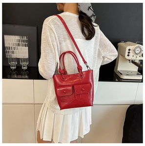 Detail of red crocodile texture handbag with dual front pockets and tied handle design