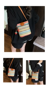 Close-up of rainbow striped woven bucket bag with leather flap and strawberry charm