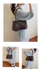 Close-up of retro brown leather shoulder bag with a heart-shaped charm and sleek straps