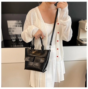 Detail of black crocodile texture handbag with unique knot handle and front pockets