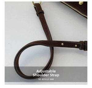 Detail of adjustable suede shoulder strap with gold metal studs on a brown shoulder bag
