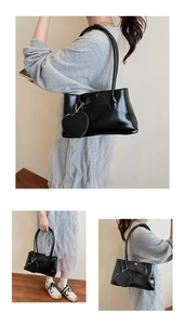 Detail of black glossy underarm bag with decorative heart-shaped coin purse attachment