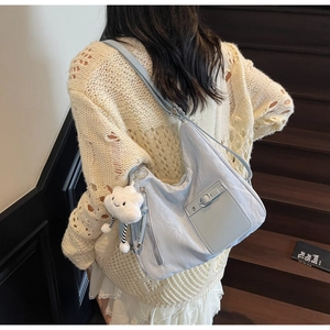 Detail of light blue hobo bag with pleated texture and plush cloud charm on model