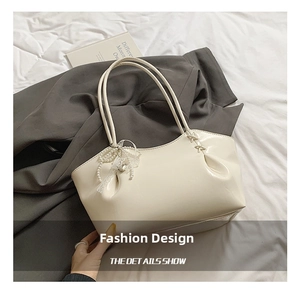 Détail du sac à bandoulière crème avec pendentif en perles et nœud en dentelle