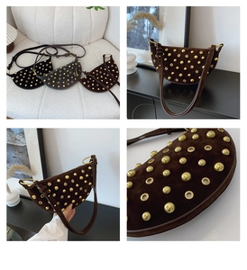 Detailed close-up of a suede crescent shoulder bag with vintage gold studs and metal eyelets