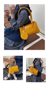 Detail of yellow PU leather shoulder bag with matching heart-shaped pendant charm
