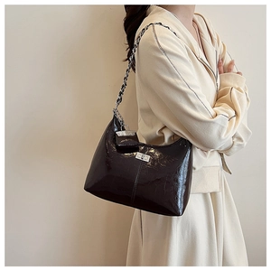 Détail du sac sous l'aisselle en cuir verni marron foncé avec chaîne et mini pochette