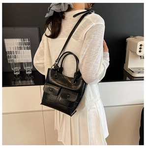 Detail of black crocodile texture handbag with dual front pockets and shoulder strap