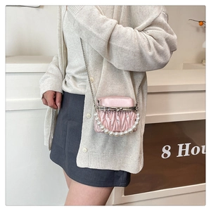 Detail of pink pleated mini bag with pearl handle and silver chain strap for women