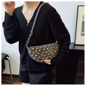 Close-up of crescent shoulder bag featuring gold studs on charcoal suede material