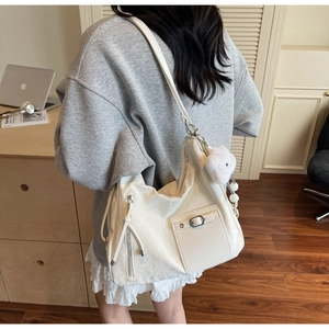Detail of off-white large capacity tote bag with decorative zippers and plush charm