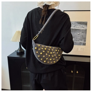 Detail of grey suede crescent bag with gold rivet studs worn on the shoulder