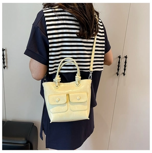 Close-up of beige faux crocodile texture bag with double pockets and knotted handle