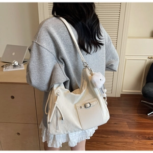 Detail of minimalist beige leather tote with metal buckle and plush lamb charm accessory