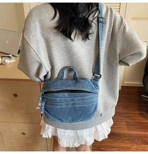 Détail du sac hobo en jean délavé avec double fermeture éclair et pompons en denim tendance