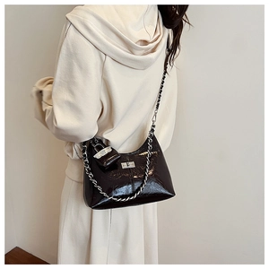 Detail van glanzende zwarte laklederen hobo-tas met zilveren ketting en slotje