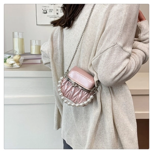 Detail of pink quilted handbag featuring pearl handle and silver chain on a model