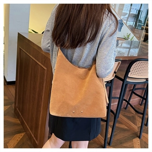 Detailed view of a brown suede tote bag with gold stud accents in a cafe setting