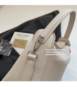 Gros plan de la boucle en métal argenté et texture litchi du sac seau blanc cassé