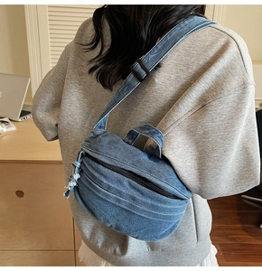 Detail of blue denim crossbody bag showing textured fabric and adjustable strap with tassels