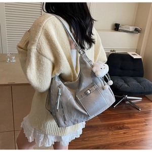 Detail of silver metallic tote bag with cloud pendant and chain strap on shoulder