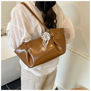 Détail du sac cabas en similicuir brillant caramel avec nœud en dentelle et perles