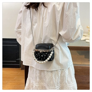 Detail of black pleated crossbody bag with large pearl handle and metal chain strap