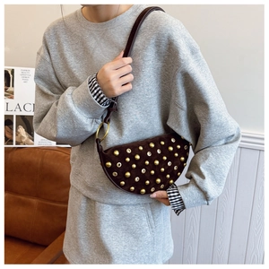 Detail of dark coffee suede crescent bag featuring golden rivets and chic metal eyelets