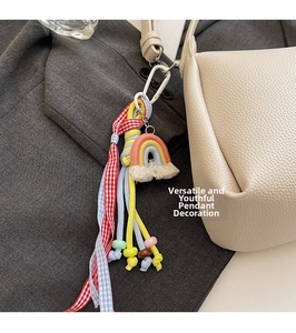 Pendentif arc-en-ciel tissé coloré avec pompons et rubans sur sac seau en cuir blanc