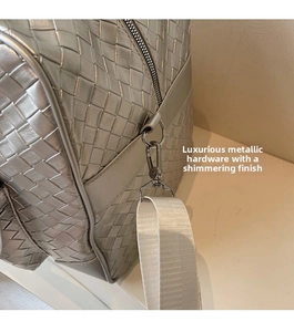 Close-up of silver woven travel bag showing metallic hardware and premium fabric strap