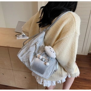 Detail of silver tote bag with crinkled texture, zipper pockets, and cloud plush charm