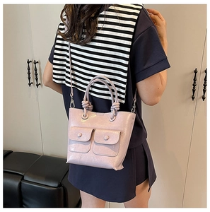Detail of lavender croc-effect handbag featuring front pockets and knotted handle
