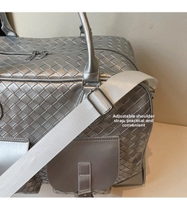 Close-up of silver woven travel bag showing adjustable shoulder strap and metal texture