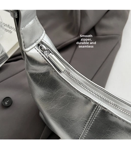 Close-up of smooth silver metallic zipper closure on textured synthetic leather bag